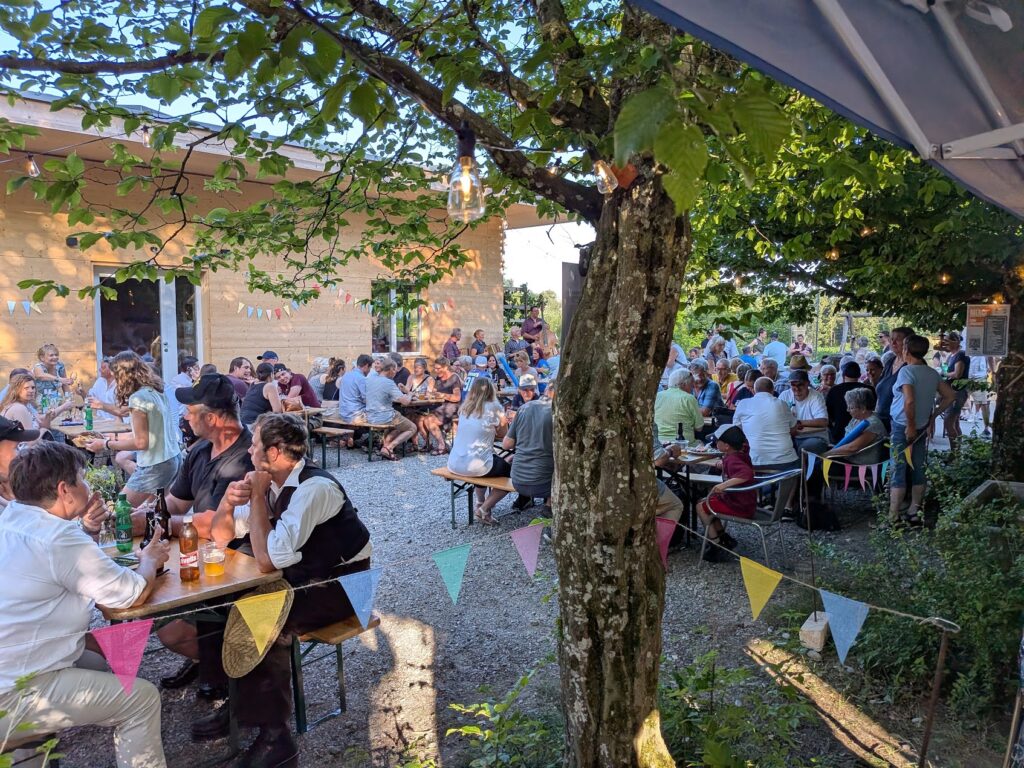 Dorffest im Garten mit vielen Besucherinnen und Besuchern an lauen Sommerabend